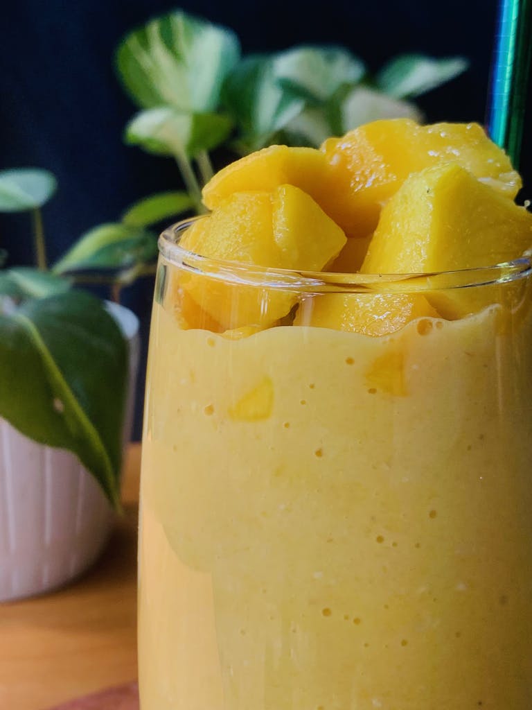 Delicious mango smoothie in a glass with fresh fruit chunks, perfect for a healthy treat.